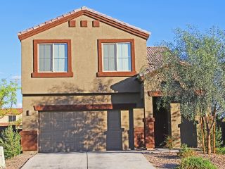 Front view of a suburban home with a new garage door and fenced yard in Goodyear.