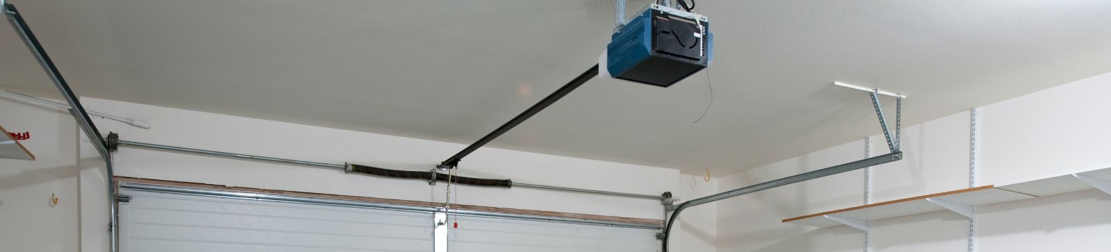 Clean garage interior featuring a mounted opener, spring system, and new sectional door by Goodyear AZ professionals